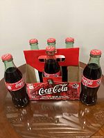 Front view of all six sealed commemorative Coca-Cola bottles in carrier
