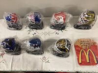 Seven sealed miniature goalie masks on bases, overall lot view