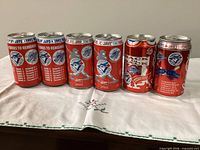 Front view of six of the commemorative Coca-Cola cans showing Blue Jays graphics and text