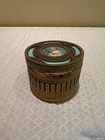 Angled view of closed gilt bronze trinket box showing portrait miniature and decorative body