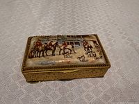 Top view showing painted equestrian scene panel and gilt metal surround