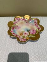 front view of scalloped porcelain plate showing floral design and gilt finish