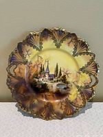 Front view showing landscape scene, scalloped rim, gilt fan motifs