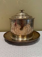 front view of engraved silver-plated biscuit barrel on underplate