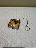 Closed compact showing butterfly wing design and chain