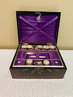 Open sewing box showing purple lined interior and all mother-of-pearl accessories in place