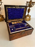 Open vanity box showing blue silk interior and compartments