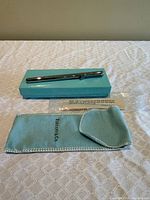 Pen resting on Tiffany blue box with suede pouch and plastic sleeve visible