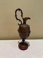 Full view of metal ewer on marble base front angle