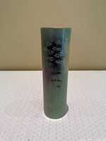 Full front view of tall green cylindrical vase with floral relief