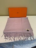 Scarf folded with fringe visible, Hermès box behind