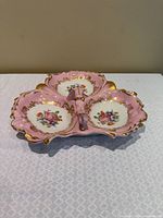 Top view of pink divided serving dish showing three sections, floral decoration and gilt detailing