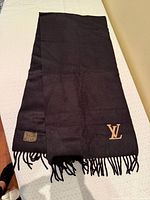 Full view of black cashmere scarf showing LV logo and fringe