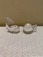 Two clear glass fish paperweights on cloth surface