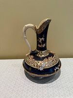 Front view showing black glaze, enamel scrollwork and bamboo-form handle