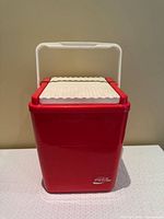 Front view of red Coca-Cola plastic cooler, lid closed, handle upright