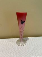 Full view of vase showing pink gradient, gold floral painting, blue butterfly, and clear ruffled foot