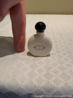 Front view showing bottle front logo and scale against finger