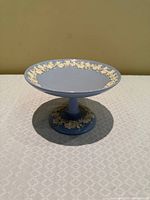 Side view of blue jasperware pedestal dish showing grapevine relief on rim and pedestal