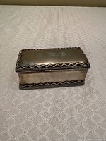 Top and side view of rectangular silver-plated inkwell box showing monogram and scalloped rim