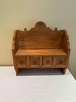Front view of wooden spice shelf showing drawers and scalloped sides