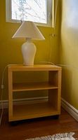 Front view of light wood veneer side table showing overall design and lamp on top (lamp not included)