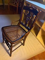 Full view of one chair showing overall design, cane seat, legs