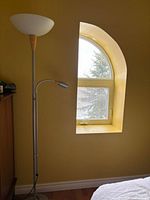 Full view of chrome floor lamp beside window, uplight shade, reading light arm, base visible