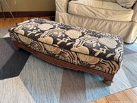 Full view of rectangular footstool on rug in front of sofa
