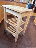 Full view of wooden butcher block cart showing top, shelves, and casters