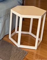 Full view of white hexagonal side table beside sofa