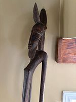Upper half of tall carved wooden figure showing face, ears and torso