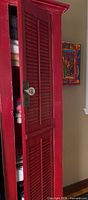 Front view of red painted louvered door cabinet