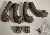 All six pieces showing four dragon-head feet, two claw plates, plastic bag visible