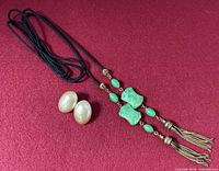 Earrings and full length of tassel necklace laid on red background