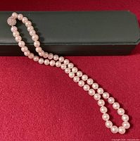 Full view of knotted pearl necklace laid out showing clasp and pearl strand