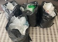 Four black garbage bags filled with bubble wrap on carpet