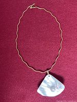Full view of sterling silver necklace showing wavy chain and shell pendant with blister pearl