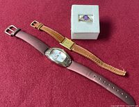 Overview of ring and two watches on red surface