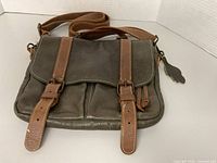 Front view showing flap, buckle straps, adjustable strap