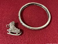 Sterling silver bangle and ice skate charm on red background