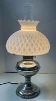Lamp lit showing chrome base, milk glass shade, chimney