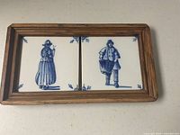 Framed pair of blue and white ceramic tiles showing Dutch man and woman