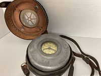 Clock in open leather case showing dial and housing