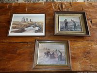 Three of the framed prints laid out on a wooden surface