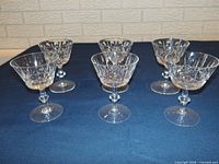 Six crystal stem glasses arranged on dark cloth
