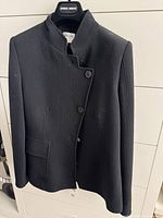 Front view of black textured blazer on hanger