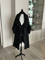 Front view of black Giorgio Armani overcoat on mannequin showing belt and shawl collar