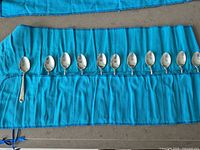All 12 teaspoons laid out in felt roll