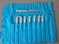 Full view of eight knives in blue Birks felt roll